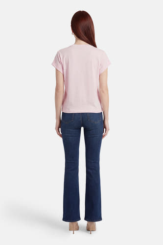 T-shirt Guess rose à manches courtes, vu de dos, combiné avec un jean bleu foncé et des talons.