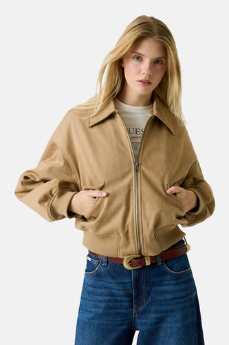 Manteau court brun de Guess avec des manches longues, associé à un jean bleu marine.