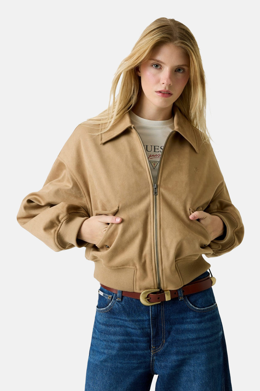 Manteau court brun de Guess avec des manches longues, associé à un jean bleu marine.