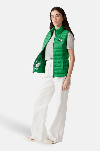 Gilet vert de JOTT, avec coutures verticales, porté sur une chemise grise et un pantalon blanc.