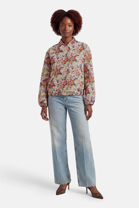 Veste courte multicolore de COLOURFUL REBEL, à motif floral, portée avec un jean bleu et des talons marron.