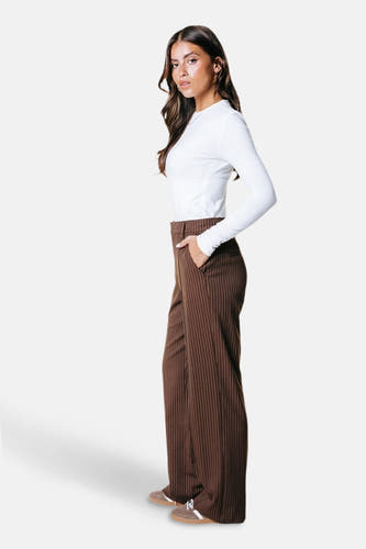 Pantalon de costume marron de COLOURFUL REBEL, avec des rayures verticales, porté avec un chemisier blanc, en vue latérale.