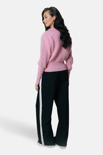 Pantalon noir avec une rayure latérale de COLOURFUL REBEL, vu de derrière, associé à un gilet rose.