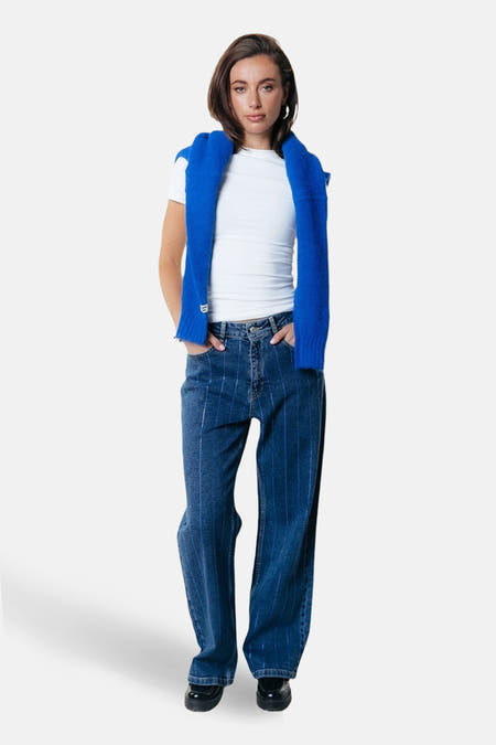 Donkerblauwe wijde jeans van COLOURFUL REBEL, met krijtstrepen en gedragen met een wit shirt en blauwe trui.