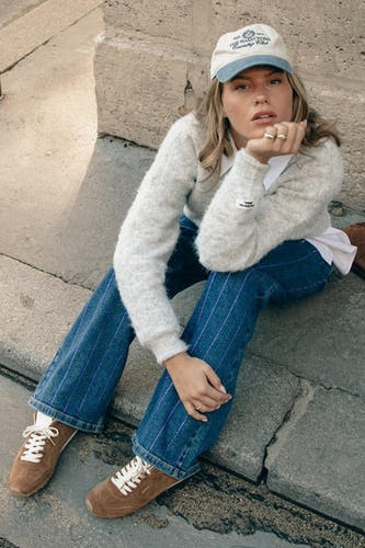 Donkerblauwe wide jeans van COLOURFUL REBEL, met verticale strepen en gecombineerd met bruine sneakers en een gebreid vest.
