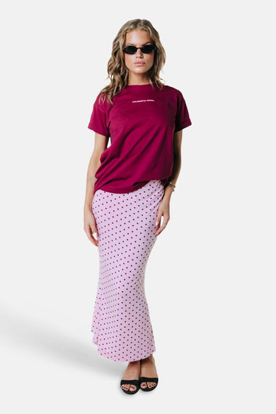 Roze lange rok met donkere stippen van COLOURFUL REBEL, geflankeerd door een paarse t-shirt en zwarte zonnebril, vooraanzicht.