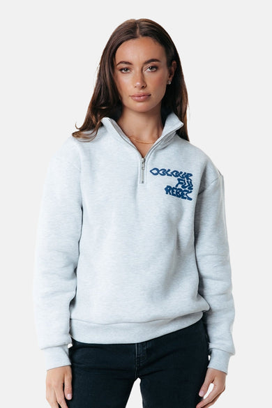 Grijze sweater van COLOURFUL REBEL met een korte rits aan de voorkant, gedragen met een gouden ketting en donkere jeans.