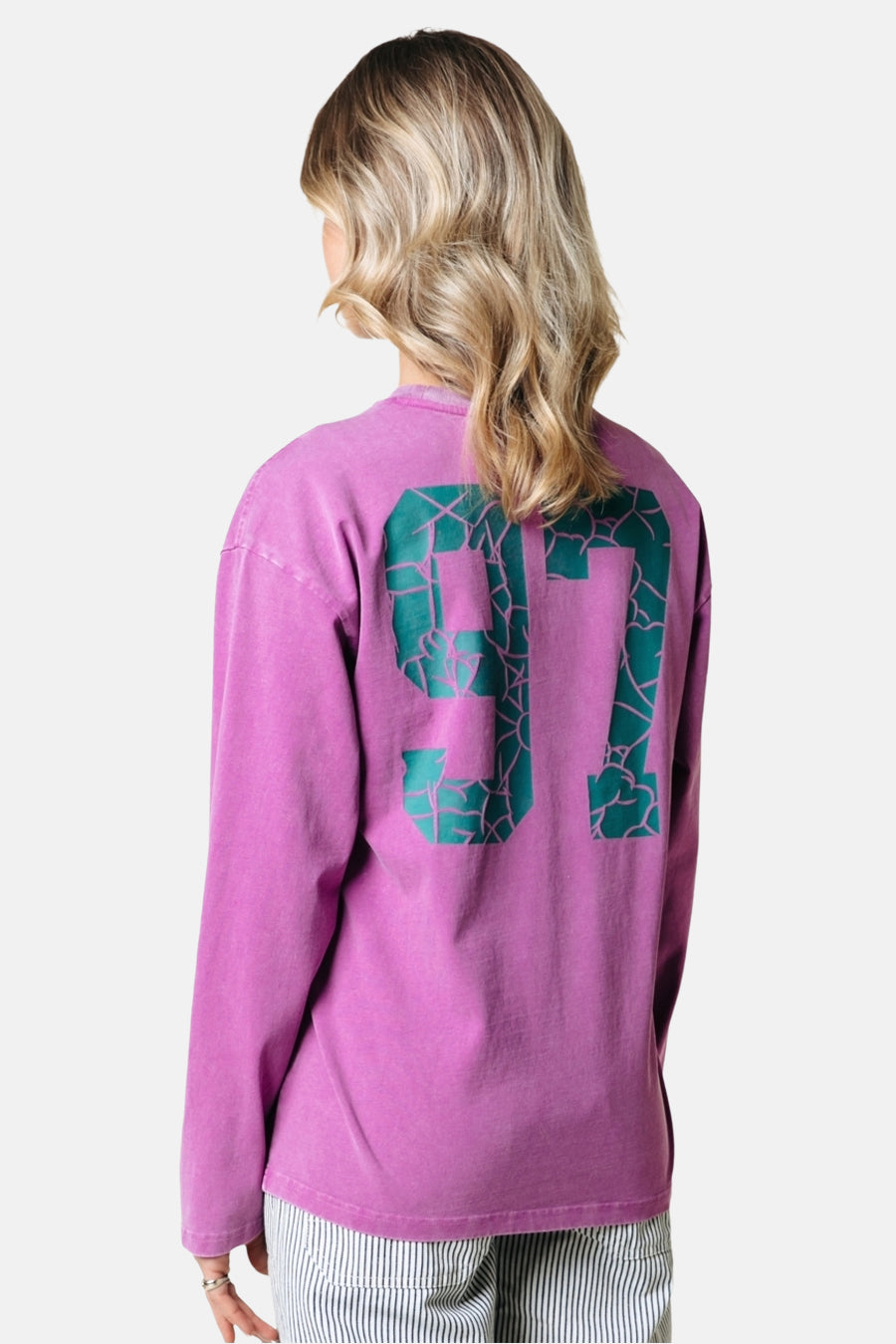 Roze T-shirt met lange mouwen van COLOURFUL REBEL, met groen nummer 97 op de rug, gedragen met gestreepte broek.