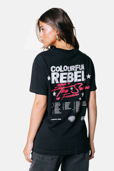 T-shirt noir à manches courtes de COLOURFUL REBEL, avec une impression sur le dos et porté avec des jeans gris.