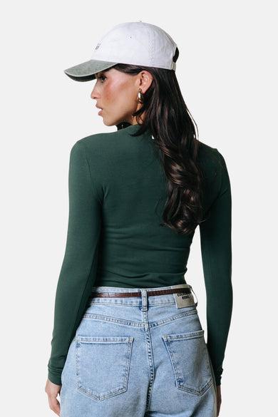 T-shirt vert à manches longues de COLOURFUL REBEL, avec une coupe longue, combiné avec un jean bleu et une casquette.
