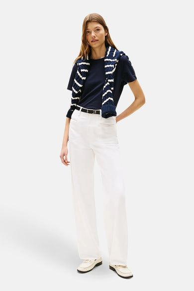 T-shirt bleu à manches courtes de Tommy Hilfiger, avec un pull rayé sur les épaules et un short blanc.