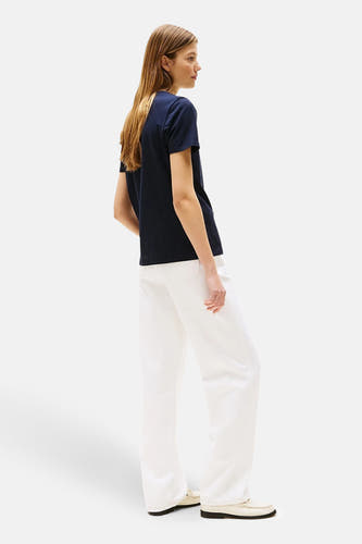 Blauw T-shirt met korte mouwen van TOMMY HILFIGER, gedragen met een witte broek en loafer-schoenen.