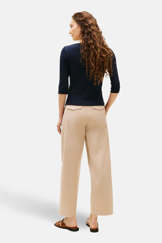 T-shirt bleu marine à manches courtes de TOMMY JEANS, associé à un pantalon décontracté et des sandales en cuir.