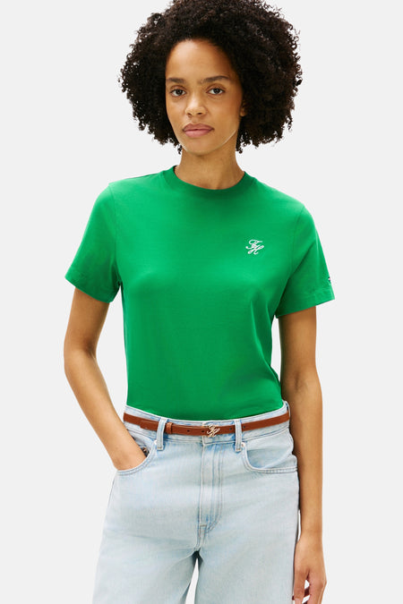 T-shirt vert Tommy Jeans de couleur verte, avec un petit logo, combiné avec une ceinture marron et un jean ample bleu clair.