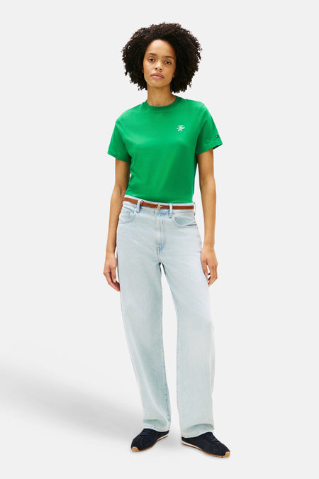 Groen T-shirt van Tommy Jeans, met een klein logo, gecombineerd met een bruine riem en wijde, lichtblauwe jeans.