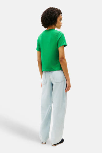 Groen T-shirt van TOMMY JEANS, gezien van achteren, gecombineerd met een wijde, lichtblauwe jeans.