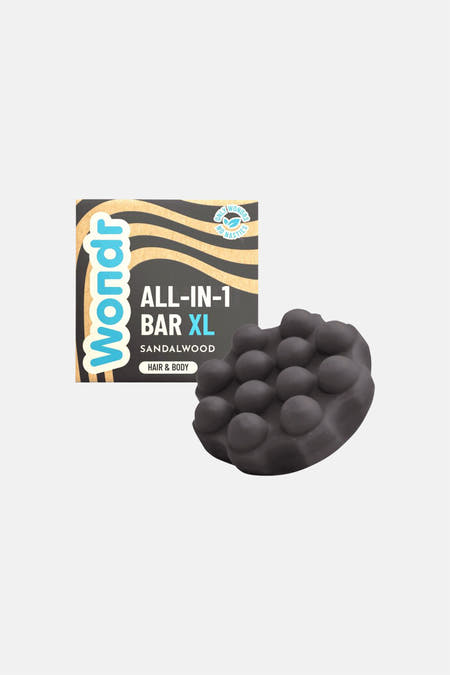 Donkere XL sandalwood all-in-1 bar van WONDR CARE met noppenstructuur, naast de verpakking.