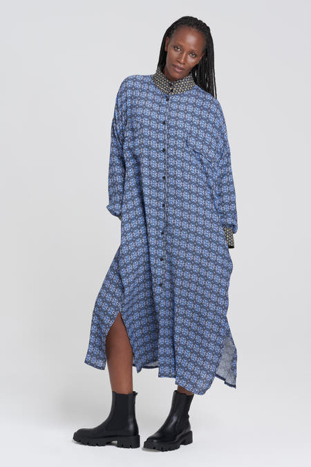 Robe bleue 3/4 de YOUNG DESIGNERS X ZEB, avec un motif géométrique et des manches longues, portée avec des bottes noires.
