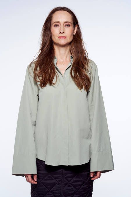 Chemise verte de YŪGEN, à manches longues et coupe décontractée, portée avec une jupe matelassée.