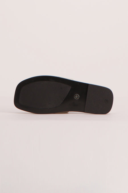 Sandales beige de YŪGEN, avec une semelle noire et une talon bas, vues de dessous.