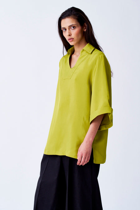Gele blouse met driekwart mouwen van YŪGEN, gedragen met een zwarte broek, tegen een witte achtergrond.
