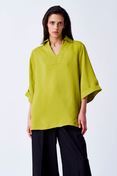 Gele blouse met driekwart mouwen van YŪGEN, met een V-hals en zwarte broek.
