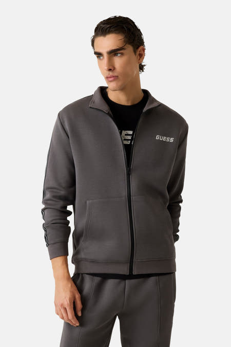 Grijs vest van Guess met ritssluiting en lange mouwen, gedragen over een zwart T-shirt.