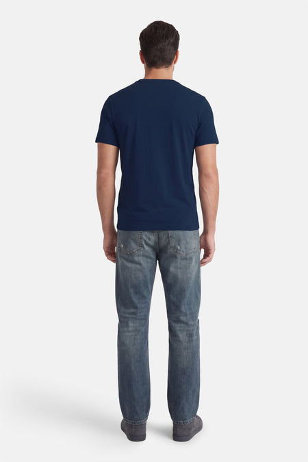 Blauw T-shirt met korte mouwen van Guess®, gezien van achteren, gecombineerd met jeans en donkergrijze schoenen.