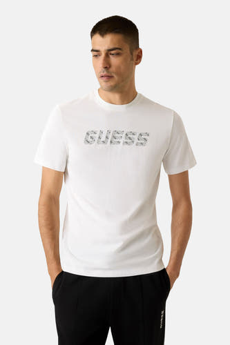 Wit T-shirt met korte mouwen van Guess, met een logo-opdruk en gedragen met zwarte broek.