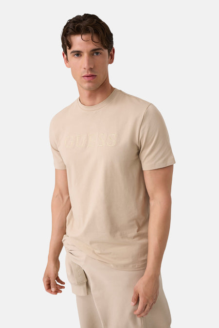 Beige korte mouwen T-shirt van Guess® met geborduurd logo op borst, gedragen door model in lifestyle shot