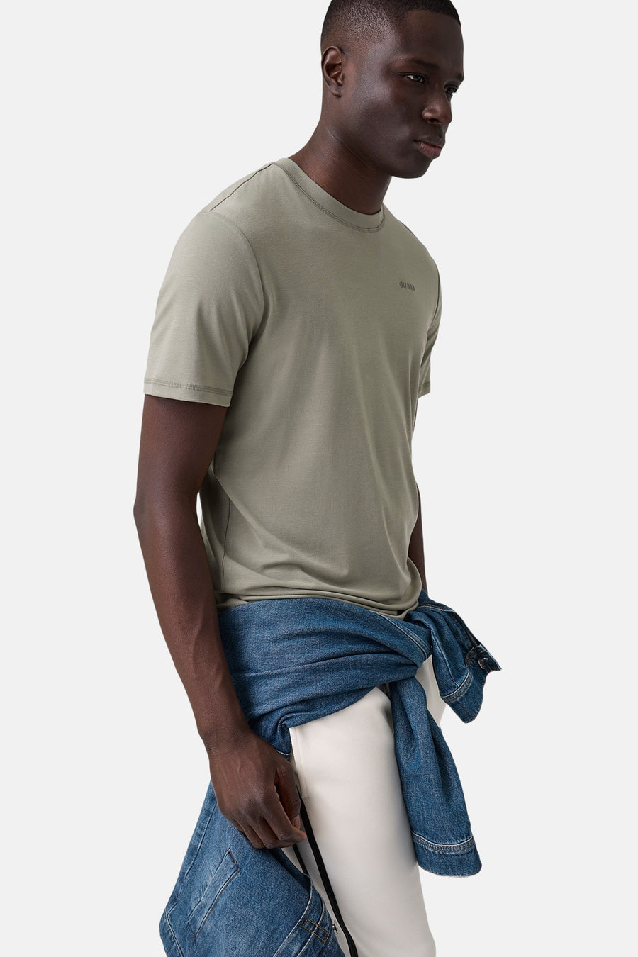 Groene korte mouwen t-shirt van Guess® met klein logo op borst, zijprofiel van model met jeansjack omheen, casual look