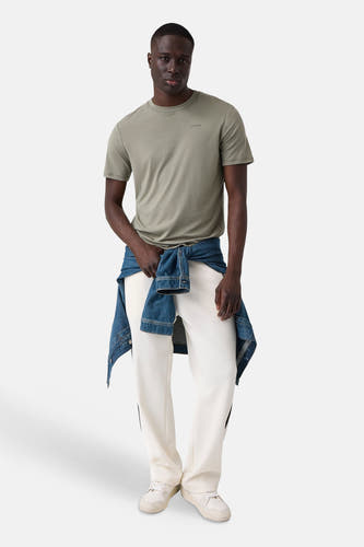 Olijfgroene korte mouwen T-shirt van Guess, met klein logo op borst, gedragen met witte broek en jeansjack, front view.