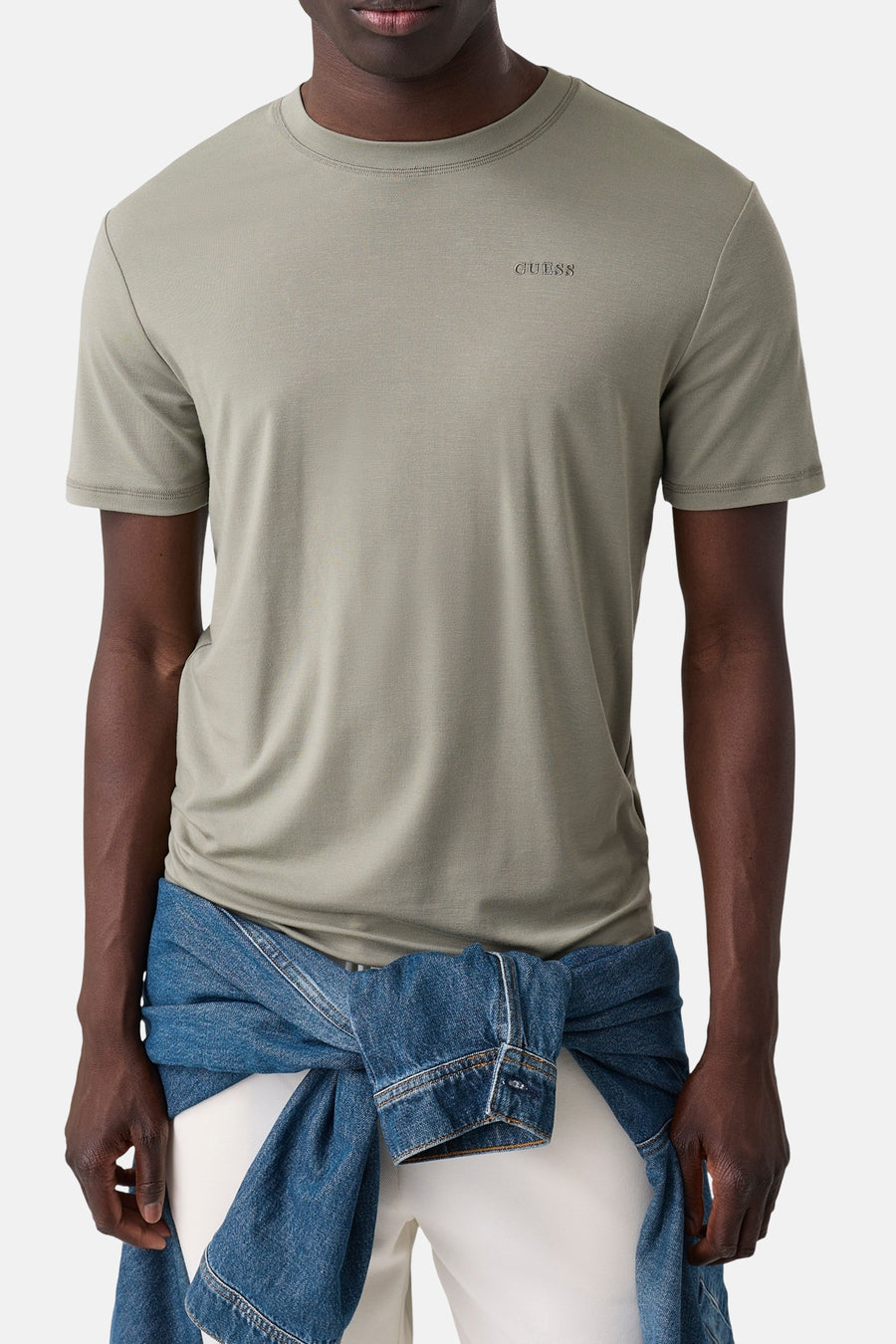 Groene korte mouwen T-shirt van Guess met klein logo op borst, gedragen met witte broek en blauw denim jasje om de taille, vooraanzicht.