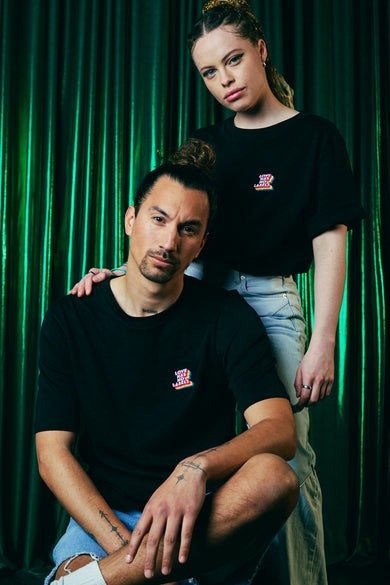 Zwarte top van ZEB STYLE LAB, met 'Love Has No Labels'-logo op de borst tegen een groene achtergrond.